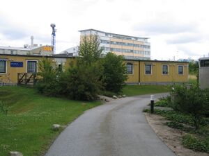 A picture of the VentureLab offices as seen from the outside, showing a one-story yellow building with a taller building in the background.